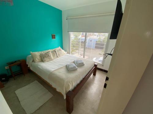 a bedroom with a bed with blue walls and a window at Hermoso departamento en Villa María in Villa María