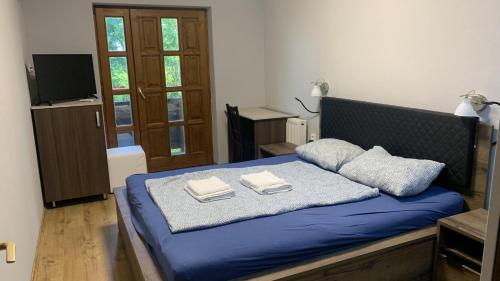 a bedroom with a blue bed with towels on it at See Haus - Podmaniczky Szállás, Bor, Balaton in Balatonföldvár