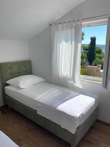a bed in a white bedroom with a window at Apartman Marla in Sevid