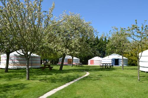 a park with tents and picnic tables and trees at Rando-Yourte in Paluel
