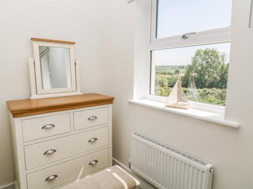 a bedroom with a dresser with a mirror and a window at Meadow Bay in Bideford