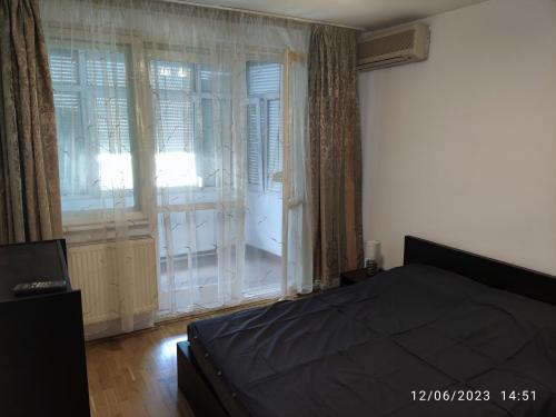 ein Schlafzimmer mit einem Bett und einem großen Fenster in der Unterkunft Fabian central apartment in Bukarest