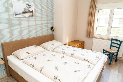 プレローにあるFeriendomizil Prerowの小さなベッドルーム(白いシーツ付きのベッド1台付)