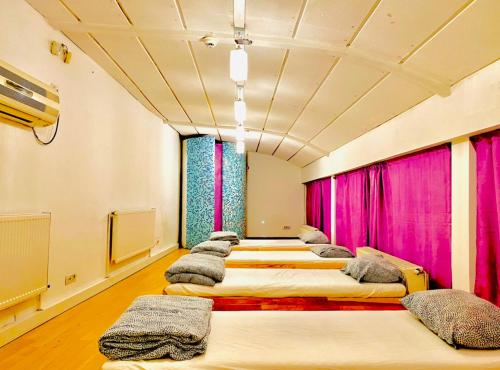 a row of beds in a room with pink curtains at A.G ROMANA HOSTEL in Bucharest