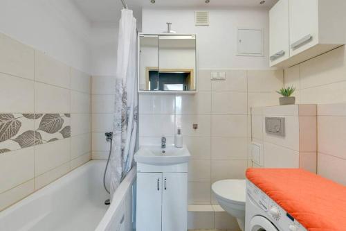 a bathroom with a sink and a tub and a toilet at Motława 2 by Grand Apartments in Gdańsk