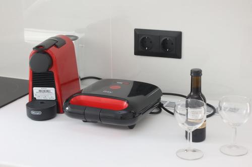 Cozy By Syros Bnb في إرموبولّي: محمصة حمراء وسوداء جالسين بجوار زجاجة من النبيذ