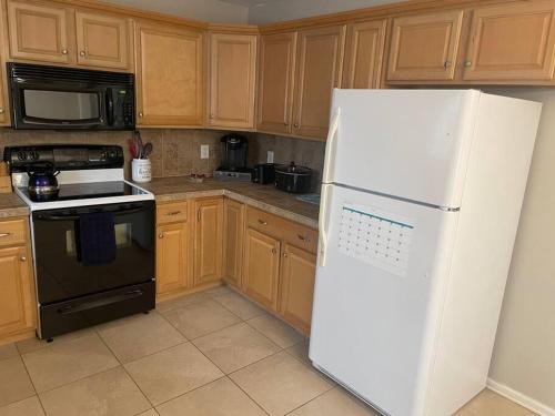 einen weißen Kühlschrank in einer Küche mit Holzschränken in der Unterkunft Reed Legacy, LLC Home in Newark