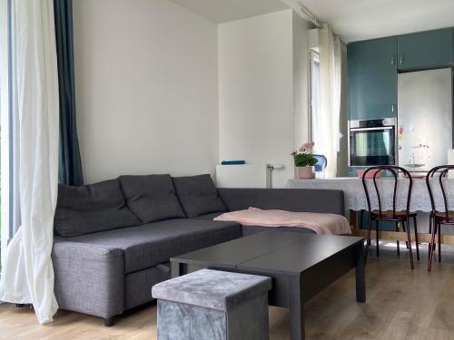 a living room with a couch and a table at Logement spacieux avec chambre privée in Noisy-le-Grand