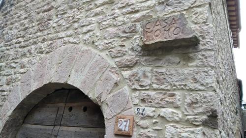 ein Steingebäude mit einer Tür mit einem Schild darauf in der Unterkunft Casa Momo in Montecchio