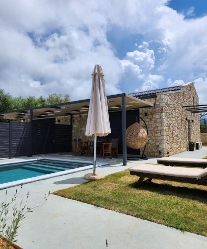 a patio with an umbrella next to a swimming pool at Elaionas Estate Perdika in Perdika