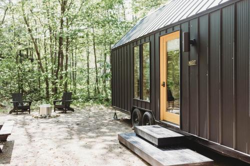 a black tiny house sitting in the woods at Lumen Nature Retreat in Woodstock
