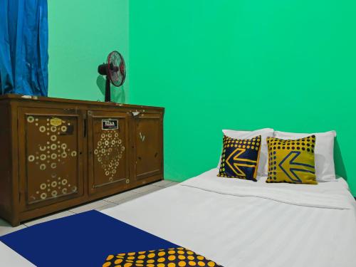 - une chambre avec un lit, une commode et un mur vert dans l'établissement SPOT ON 92610 Barokah Kostel Syariah, à Semarang