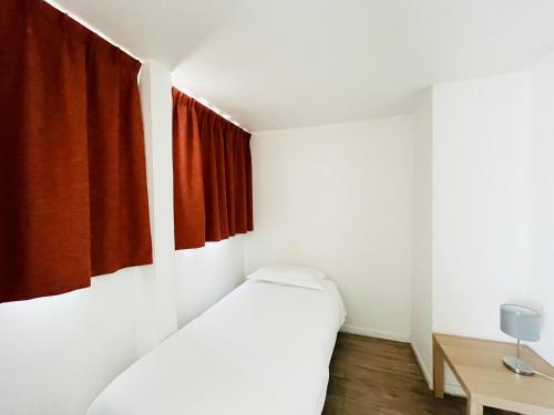 a bedroom with two beds and a red curtain at Brasilia Hôtel in Palavas-les-Flots