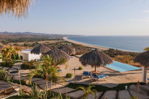 un complexe avec une piscine, des parasols en paille et l'océan dans l'établissement Villas del Sol, à Ipala