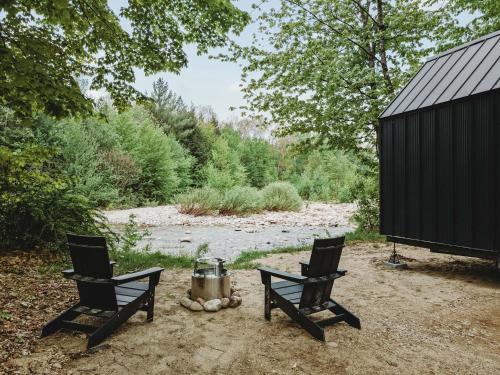 two chairs sitting next to a campfire next to a river at Lumen Nature Retreat in Woodstock