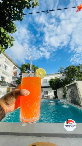 a hand holding a drink in front of a pool at Casa de Huéspedes Playas Arena in Playas