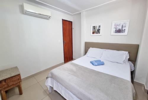 a bedroom with a white bed with a blue pillow on it at Ponta Negra Temporada in Natal