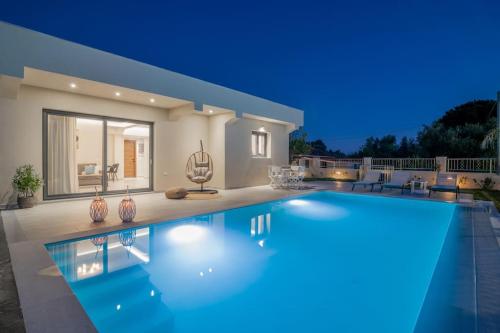 a villa with a swimming pool at night at Villa Adiola, An Unrivalled Retreat in Kalamaki