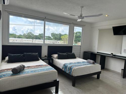 a bedroom with two beds and a large window at LUX Studio ROOM LAS PALMAS PUERTO MORELOS in Puerto Morelos