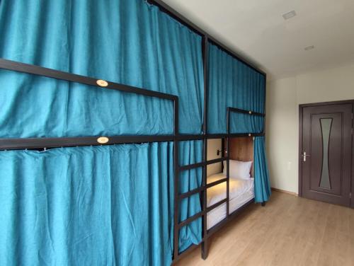 a bedroom with two bunk beds with blue curtains at ATI MTA - Eco Hostel in Borjomi
