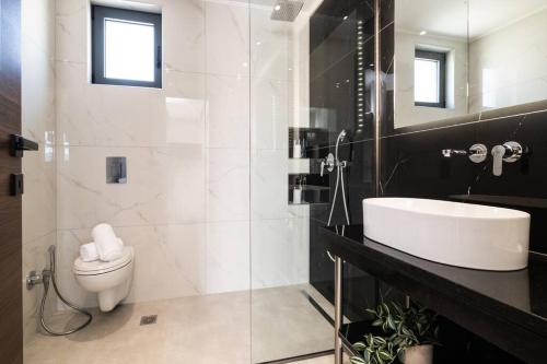 a bathroom with a white toilet and a sink at Villa Adiola, An Unrivalled Retreat in Kalamaki