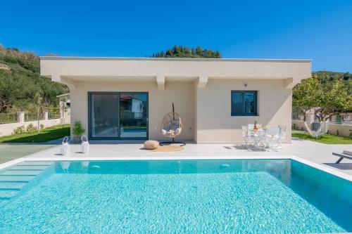 a villa with a swimming pool in front of a house at Villa Adiola, An Unrivalled Retreat in Kalamaki