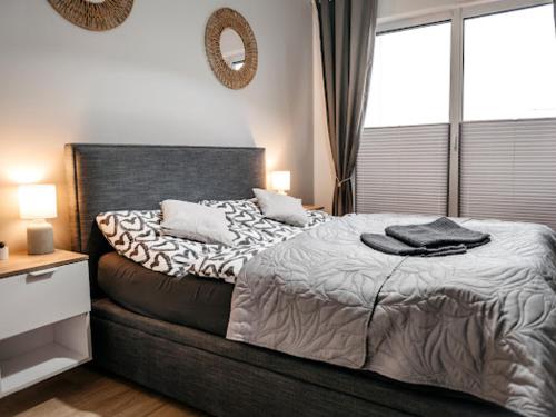 een slaapkamer met een bed en een groot raam bij Bridge Apartments&Spa apartament LILKA in Dziwnów