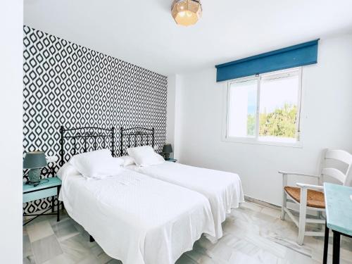 a white bedroom with a bed and a window at Novo Blue in Chiclana de la Frontera