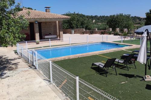 una piscina con 2 sillas y una sombrilla en Casa El Calderon, en Chella