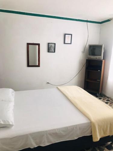 a bedroom with a white bed and a tv at Hostal la 18 in Pereira