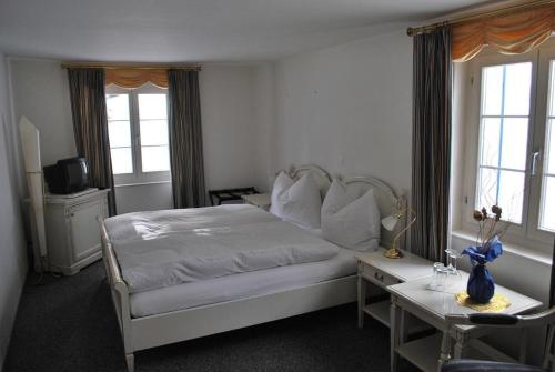 um quarto com uma cama, uma mesa e janelas em Hotel Rhonequelle em Oberwald