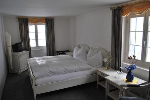 a bedroom with a bed and a table and windows at Hotel Rhonequelle in Oberwald