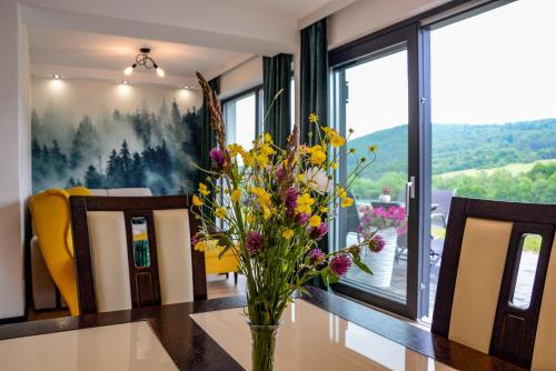 a vase of flowers on a table in a dining room at Domek Veron in Wysowa-Zdrój