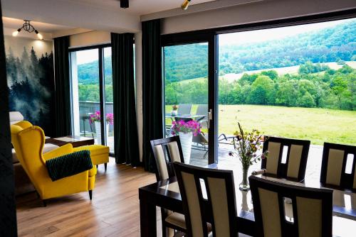 a living room with a table and chairs and a large window at Domek Veron in Wysowa-Zdrój