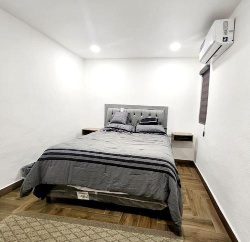 1 dormitorio con 1 cama grande en una pared blanca en Departamento Pitagoras No 2 en Ciudad Juárez