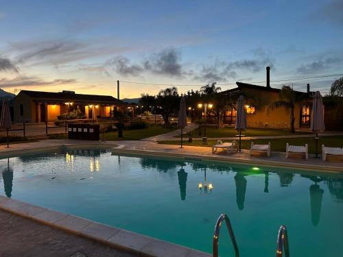 a swimming pool at dusk with a house in the background at Agriturismo l'Olivo in Calatafimi
