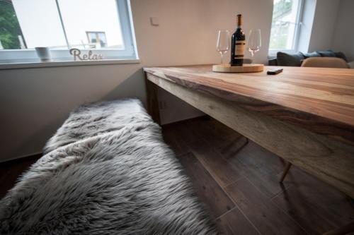 a wooden table with a bottle of wine and a couch at Apartmány na Žlábku in Horní Planá