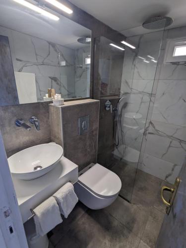 a bathroom with a toilet and a sink and a shower at Pillbox Seafront Studios and Apartments in Kardamaina