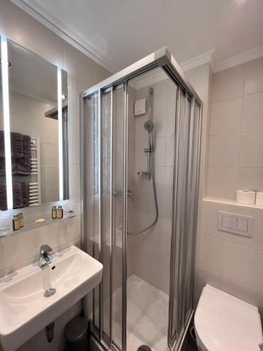 y baño con ducha y lavamanos. en Hotel Paula Norderney, en Norderney