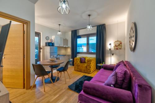 een woonkamer met een paarse bank en een tafel bij Rujan apartman Zlatibor in Zlatibor
