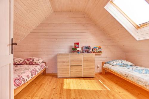 a attic room with two beds and a window at Omega Niechorze Domki Letniskowe in Niechorze