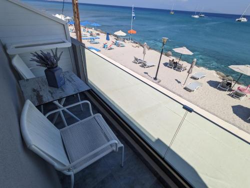 a chair on a balcony looking out at the beach at Pillbox Seafront Studios and Apartments in Kardamaina