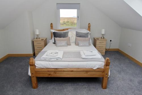 a bedroom with a large bed with pillows and a window at Sea Breeze in Clachan