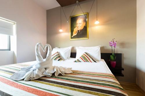 a bedroom with a white bed with a painting on the wall at Design Hotel Mr President in Belgrade