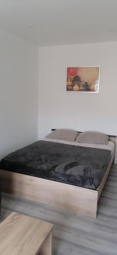 a bed with a wooden frame in a room at Appartement avec balcon et parking privé in Roanne