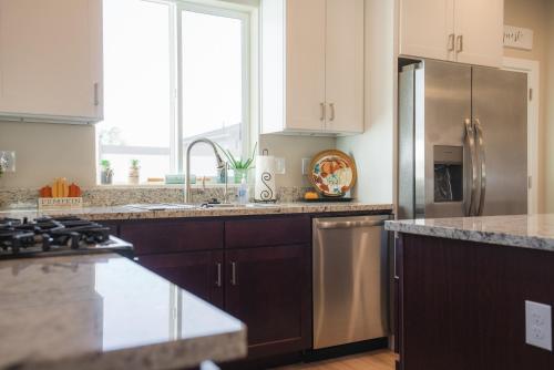 a kitchen with white cabinets and a stainless steel refrigerator at South Zion Coral Cliffs - 4 bed, 3 bath, hot tub, deck in Hildale