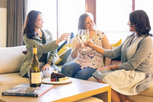 three women sitting on a couch drinking wine at Crowne Plaza Atlanta Perimeter at Ravinia by IHG in Atlanta