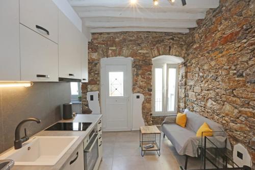 eine Küche und ein Wohnzimmer mit einer Steinmauer in der Unterkunft Stones By Syros Bnb in Ermoupoli