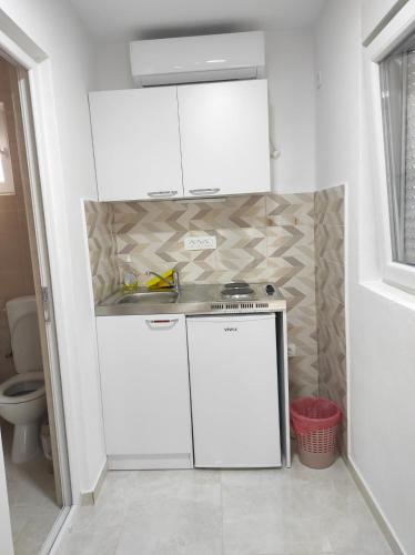 a kitchen with white cabinets and a sink at Apartmani CECA 012 Sutomore in Sutomore