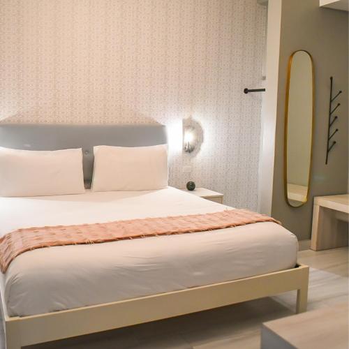 a bedroom with a bed with white pillows and a mirror at Trópica Beach Hotel in San Juan